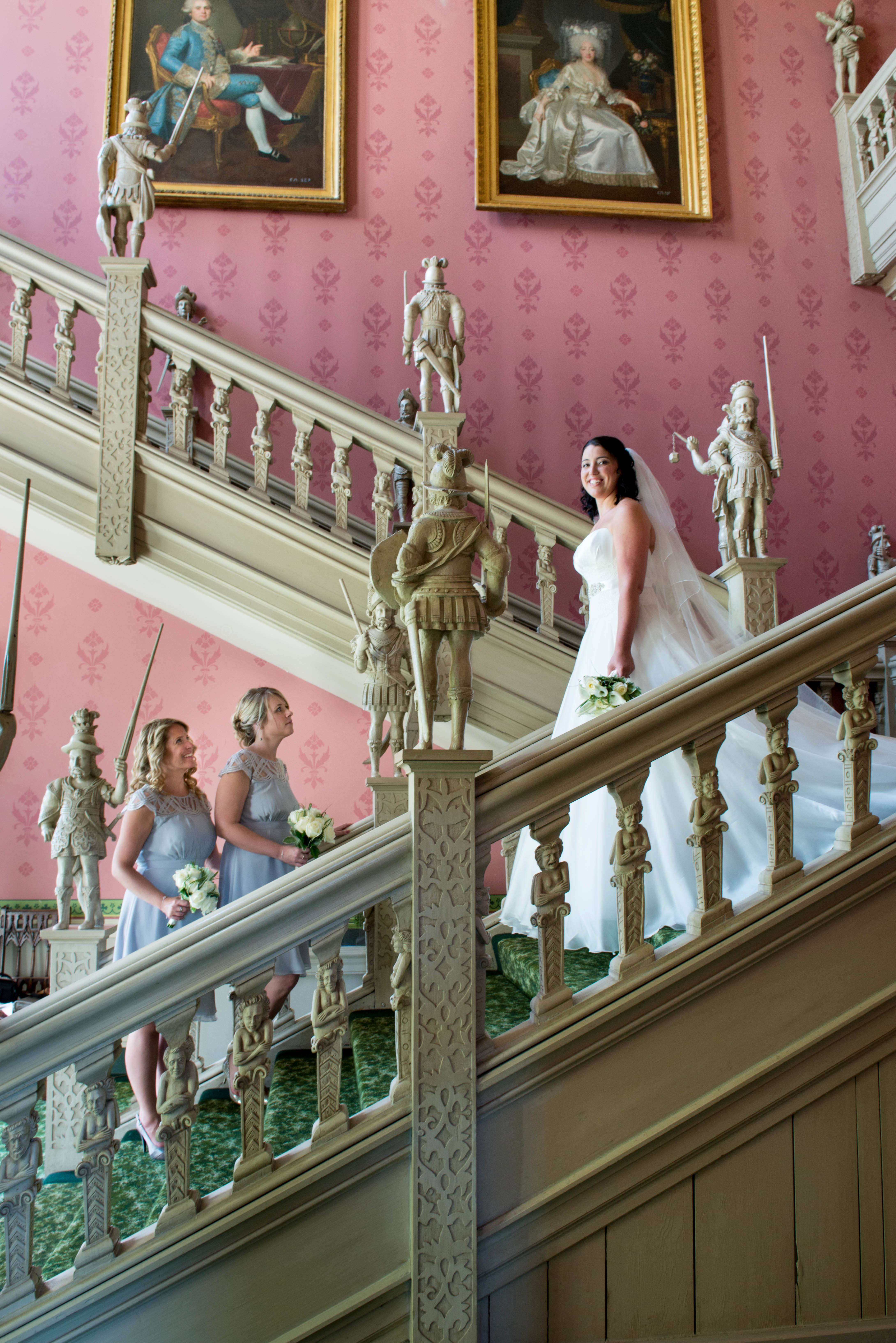 Bride meeting bridesmaids on staircase at Hartwell House